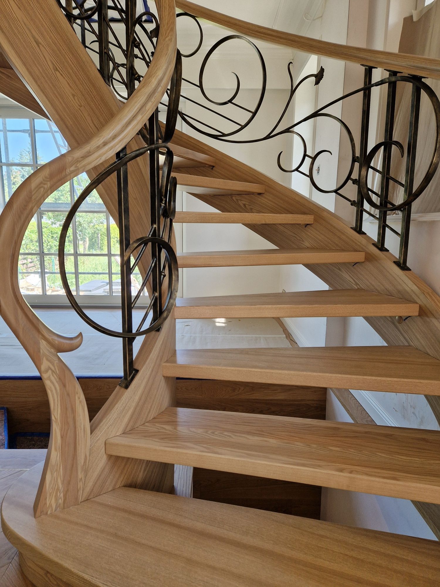 Schody gięte drewniane kręcone kute balustrady