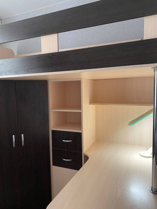 Ліжко двоповерхове разом із столом, поличками та шафою.