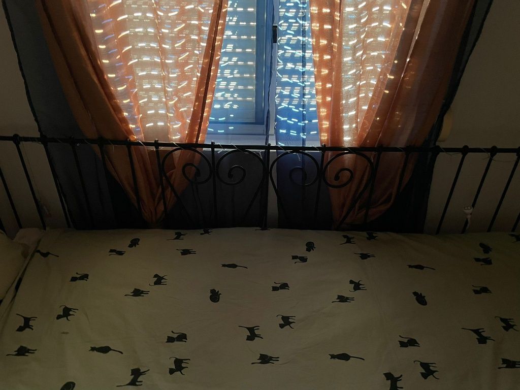 Cama de ferro preta com colchões e mesa de cabeceira