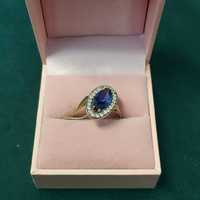 Złoty pierścionek dwukolorowy z niebieskim kamieniem i cyrkoniami