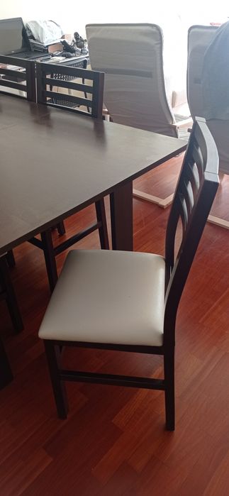 Mesa de madeira castanho escuro com seis cadeiras de pele