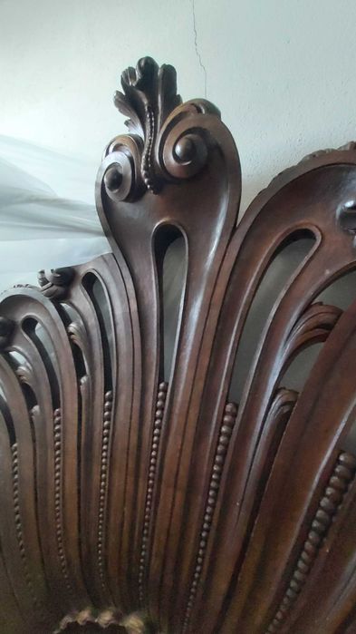 Cama casal de madeira maciça talhada com estrutura e cabecera.
