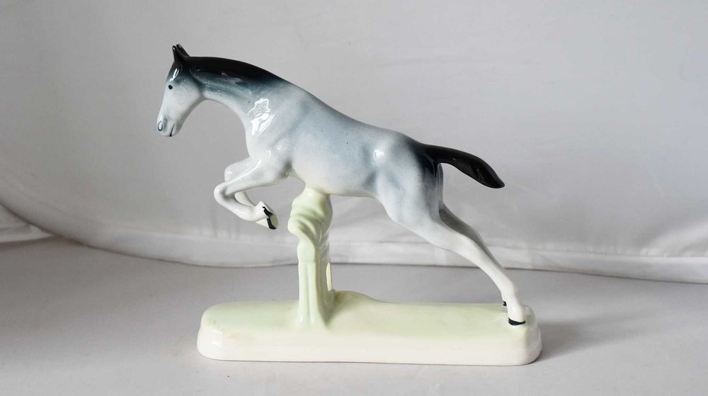 Porcelanowa figurka konia skaczącego przez przeszkodę. Chodzież