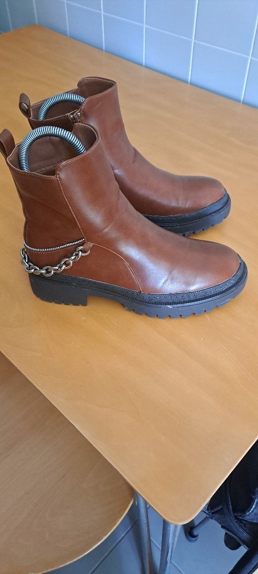 Botas cor camel de pele sintética estilo militar com correntes atrás .