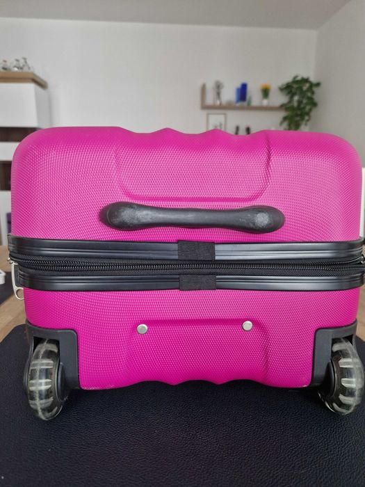 Mała kabinowa walizka w kolorze różowym.