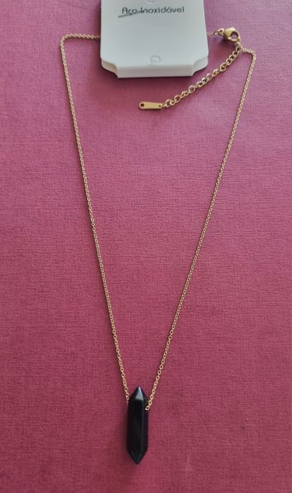 Colar dourado, em aço, com pingente em pedra natural preta lapidada.