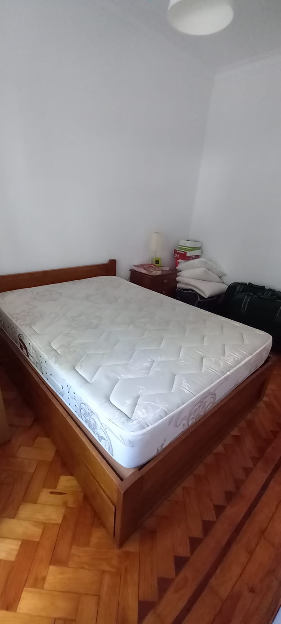 Cama de casal de madeira com colchão e mesa de cabeceira