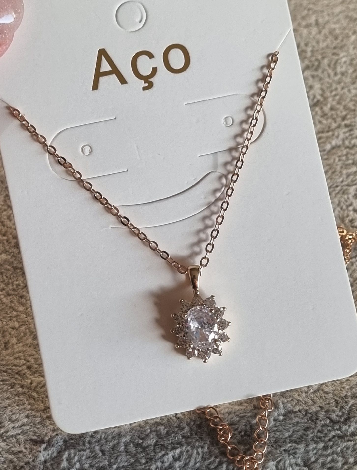 Colar dourado, em aço, com pingente de pedra de vidro. Tem extensor