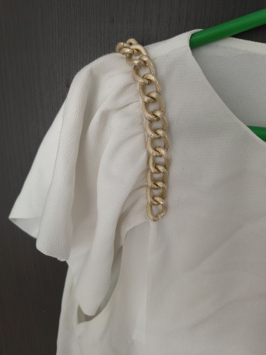 Elegancka ecru bluzka ze złotymi łańcuszkami falbany na ramionach