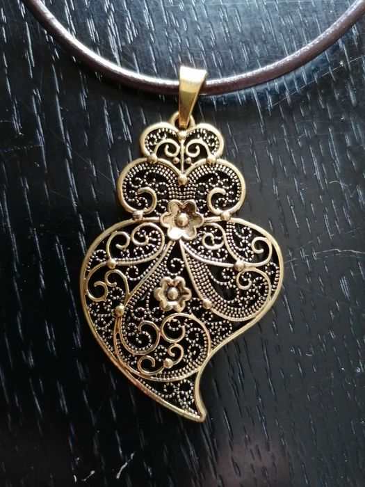 Fio em couro com pendente de coração de Viana em metal amarelo.
