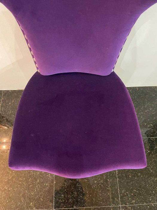 Cadeira moderna em veludo roxo com tachas metálicas de exposição