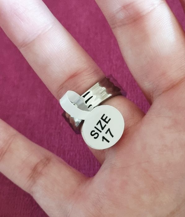 Anel prateado, em aço, com 1 coração com pedrinha preta no centro. T17