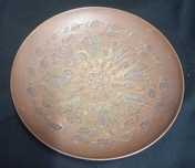 Prato decorativo antigo de cobre com um design floral gravado.
