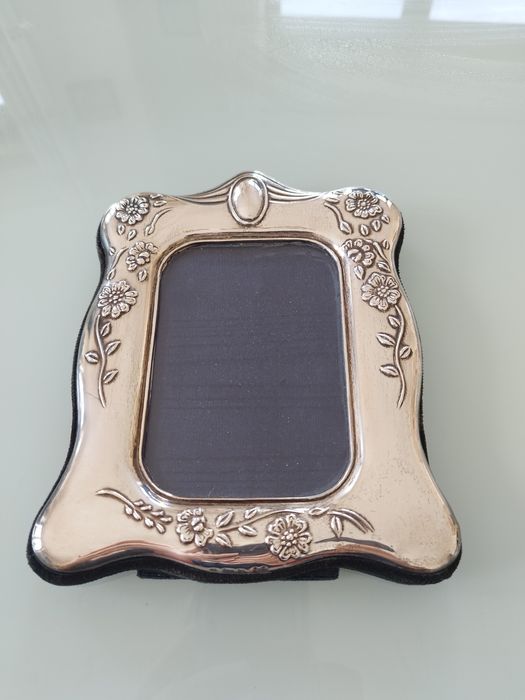 Moldura delicada com detalhes florais em relevo.

- Material: Prata
-