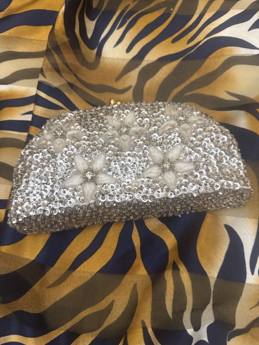 Mala com micangas prateadas e fores compoe o conjunto