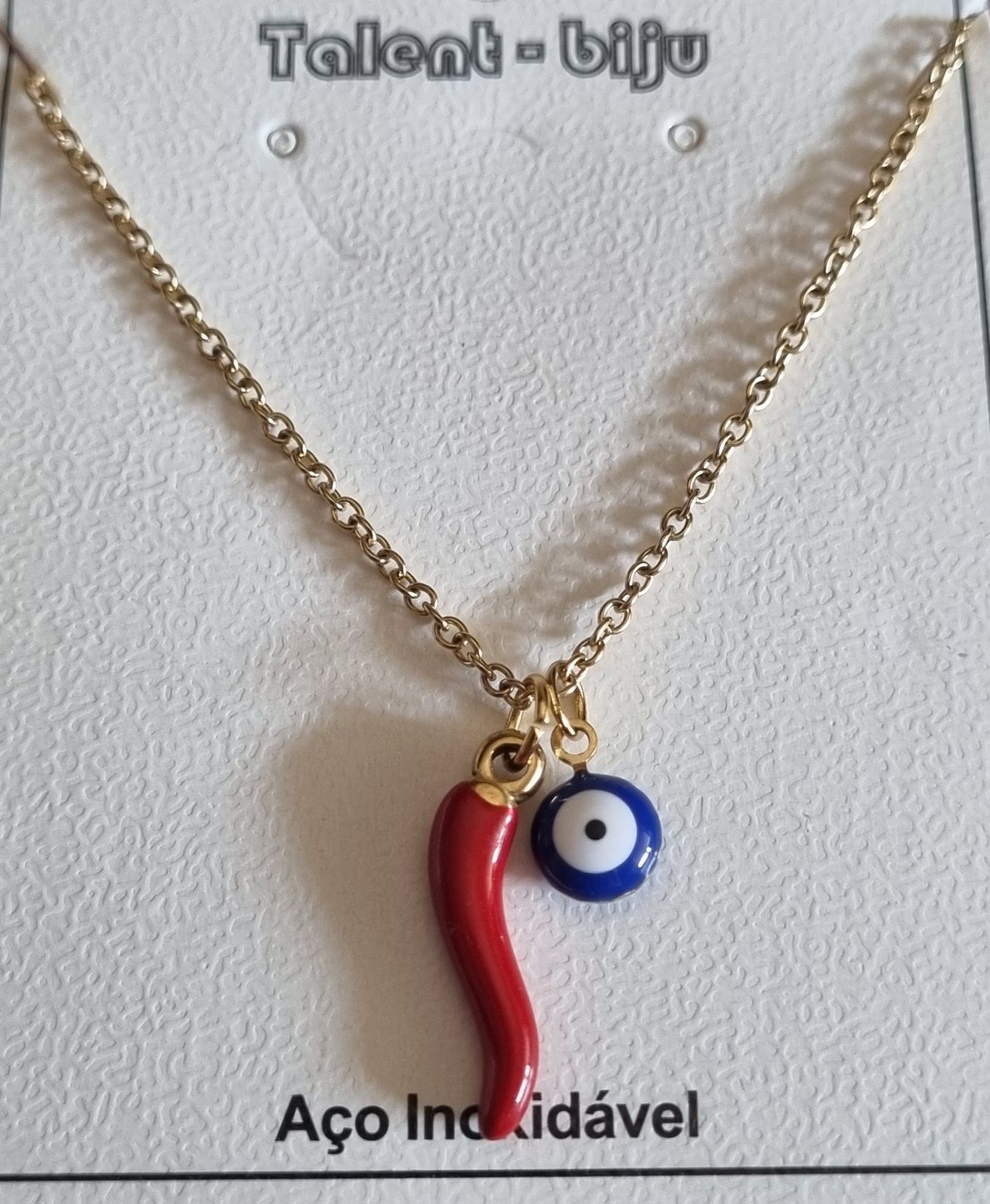Colar dourado, em aço, com pimentinha e olho grego. Tem extensor