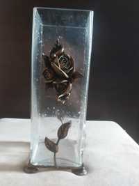Wysoki wazon z grubego szkła zdobiony kwiatem.