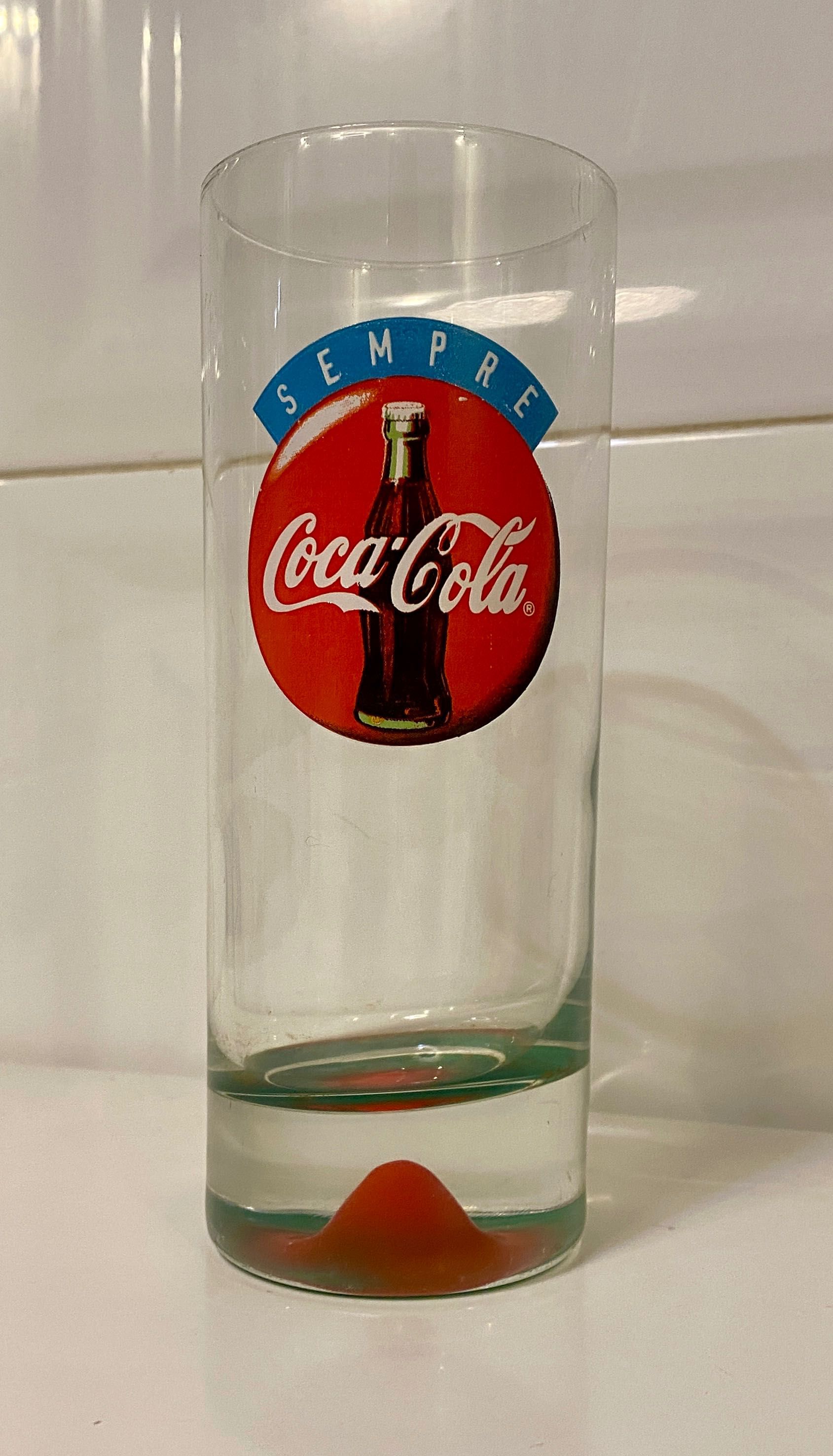 Copo antigo coca cola com relevo mama no fundo.