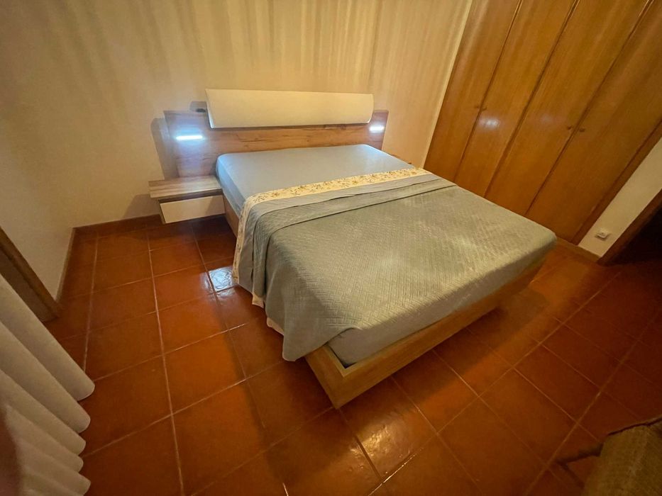 Cama de casal com mesas de cabeceira e iluminação