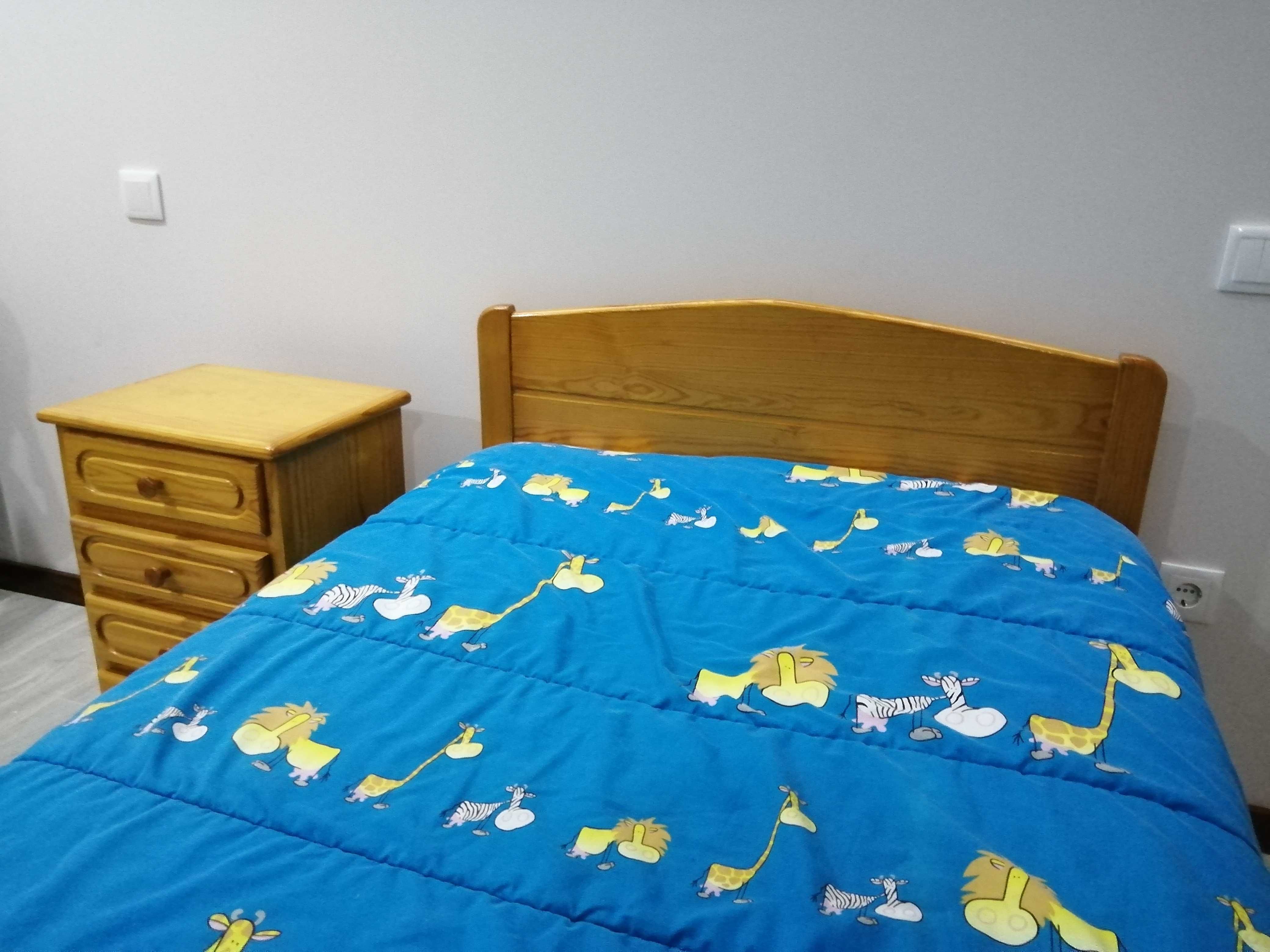 Cama de solteiro com mesinha de cabeceira.