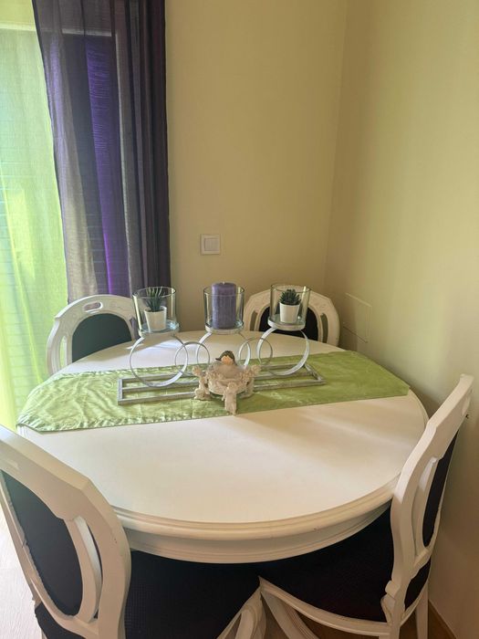 Mesa lacada de branco com quatro cadeiras forradas em tom roxo