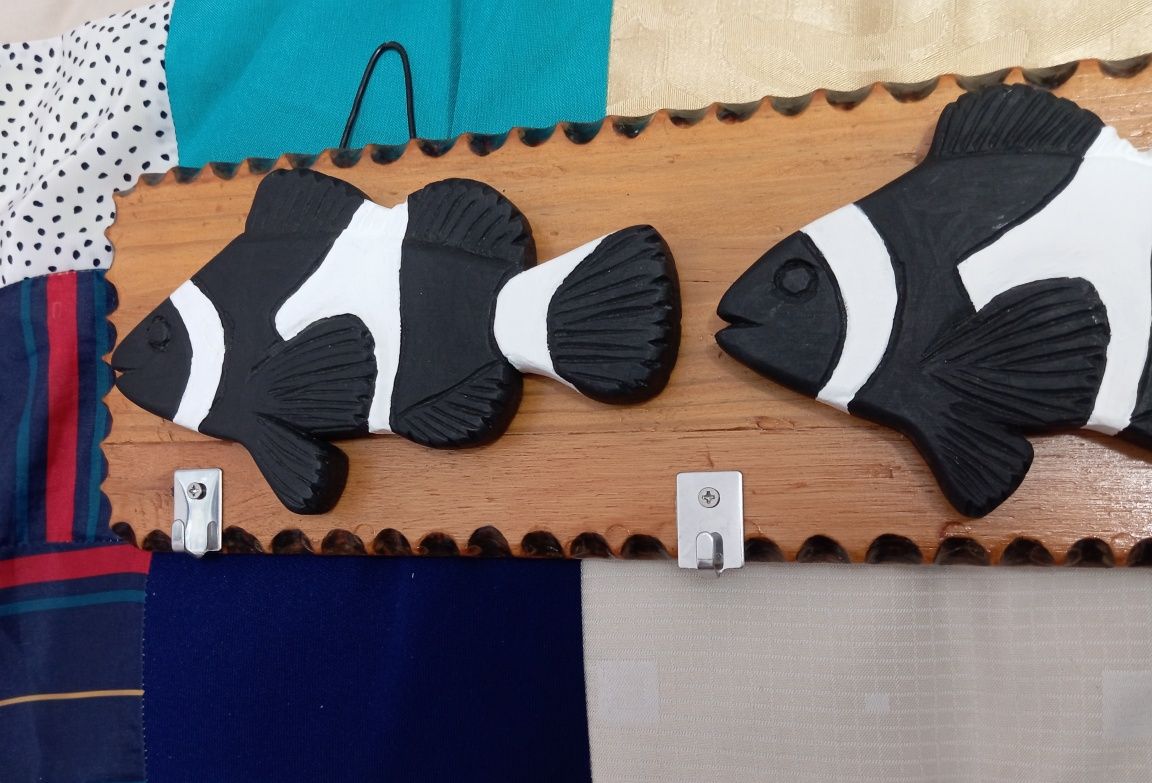 Placas decorativas em madeira com pequenos cabides.
