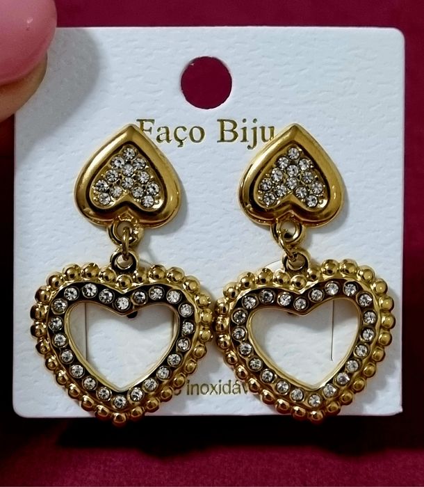 Brincos dourados, em aço, 2 corações invertidos com zirconias. De pico