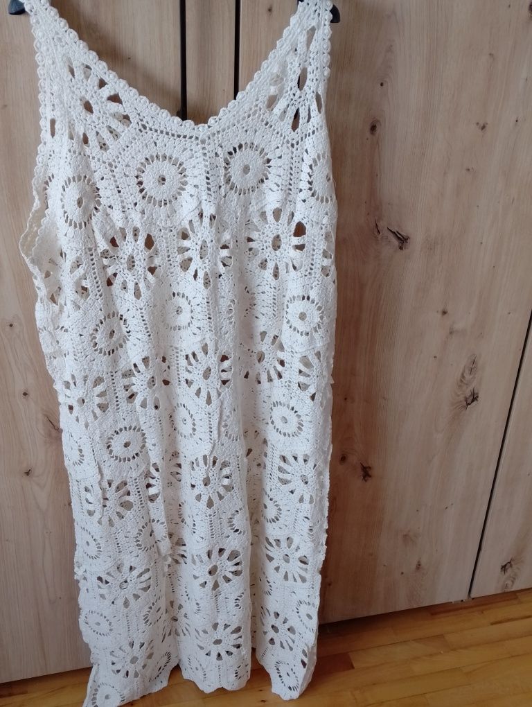 Piękna suknia ażur ma ramiączkach.