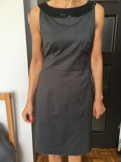 Elegancka szara sukienka marki H&M ze zdobieniem przy dekolcie.