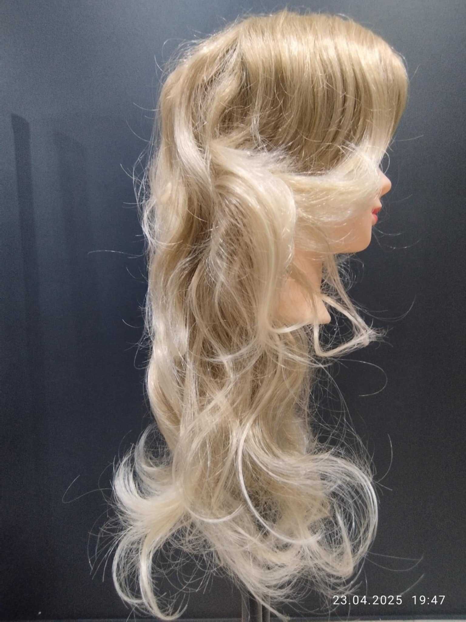 Peruka. Włosy długie cieniowane, delikatnie falowane. Kolor blond.