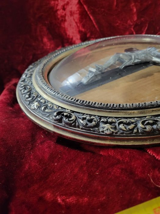 Stary krzyż w owalnej ramie za szkłem