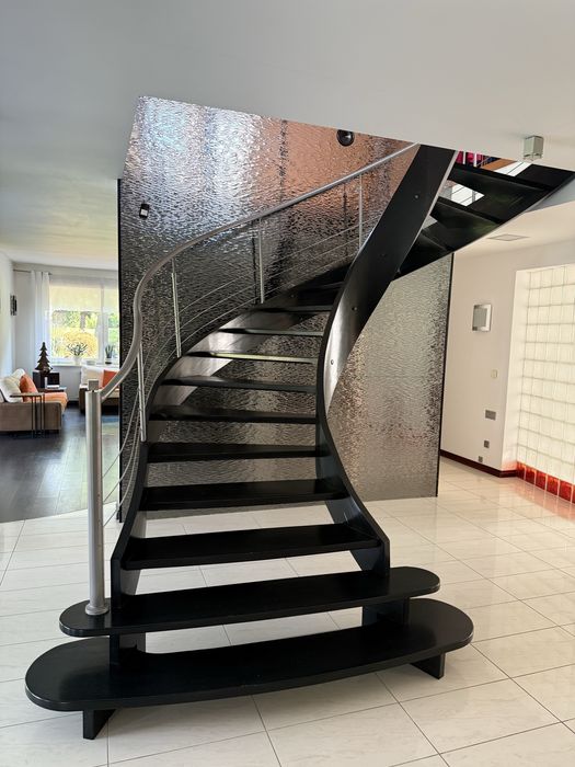 Schody drewniane kręcone z metalową balustradą