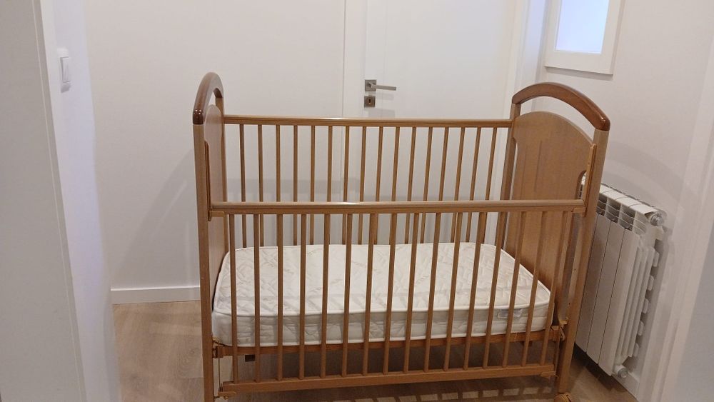 Cama de bebê, em madeira, cor bege.