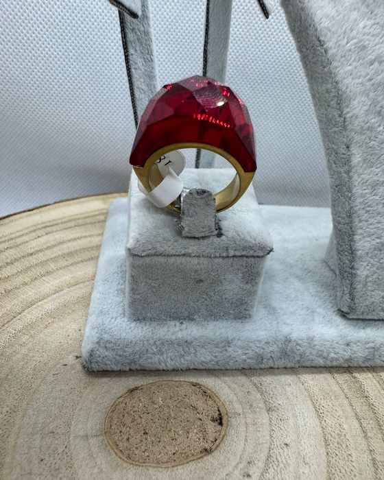 Anel dourado, em aço, com vermelho facetado na parte de cima. T17