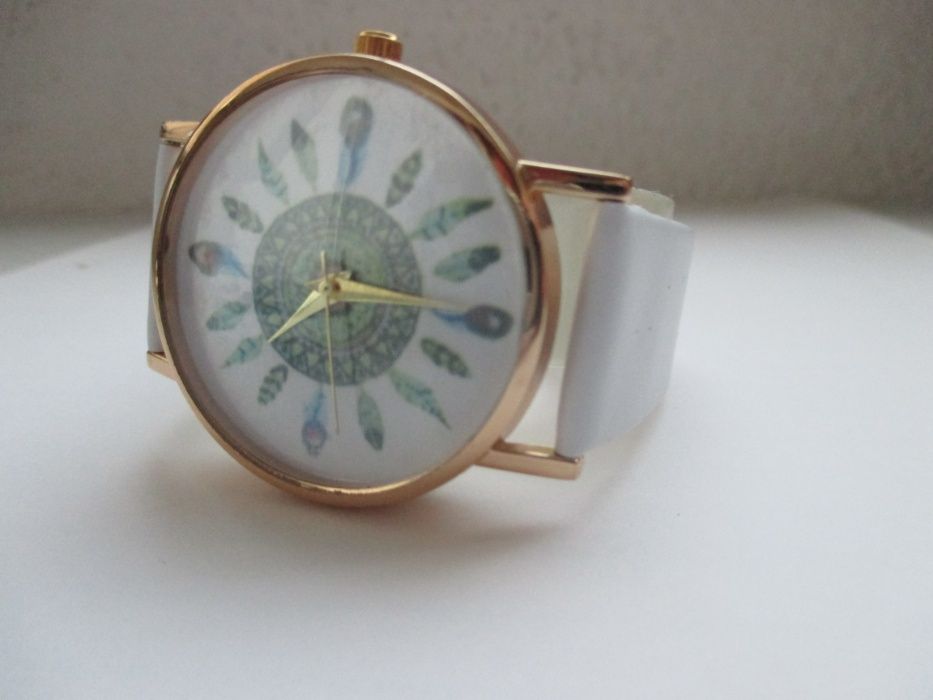 Relógio dourado com penas em fundo branco (NOVO)