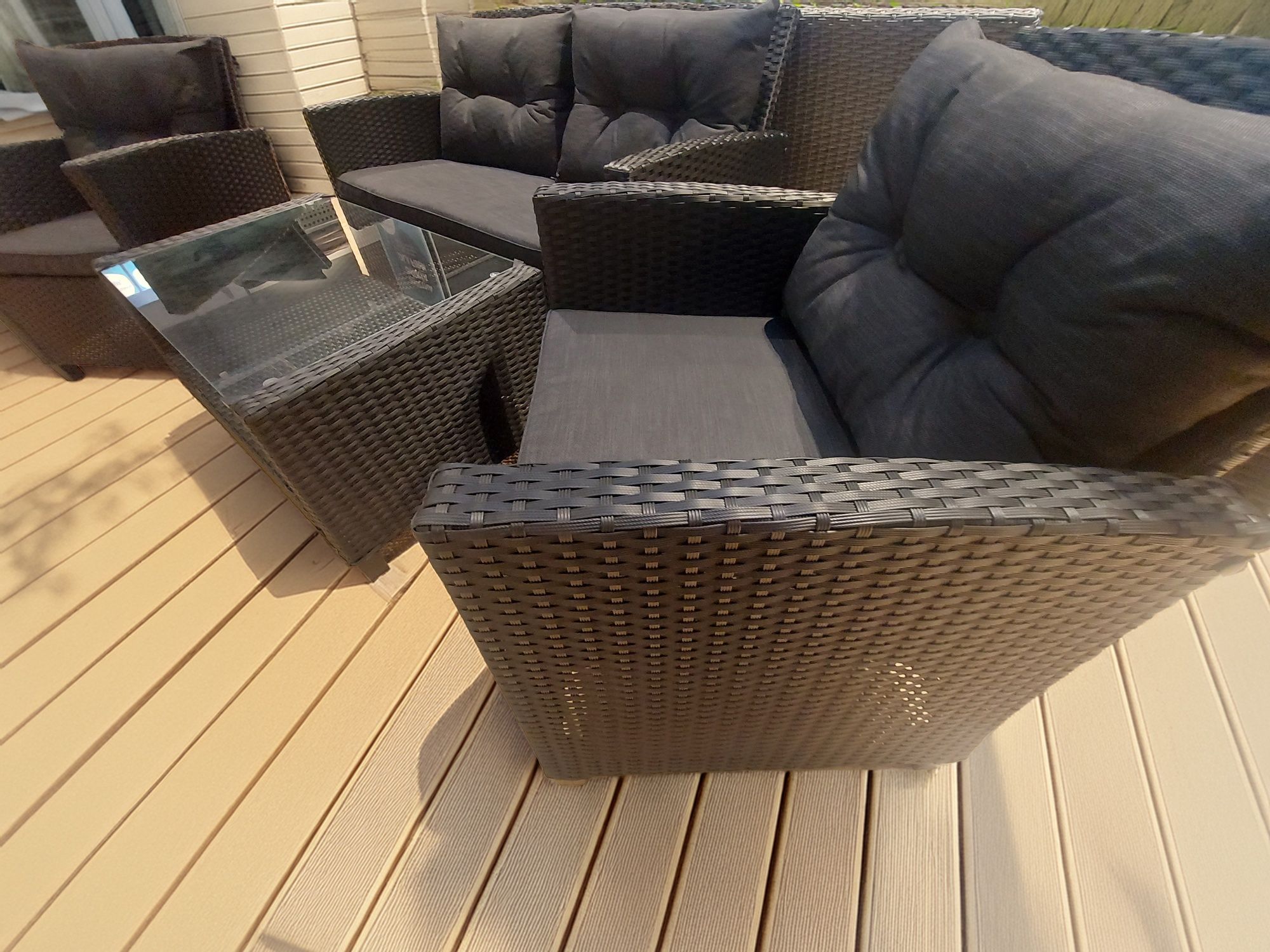 Meble ogrodowe sofa plus dwa fotele i stolik z drewnianym blatem.