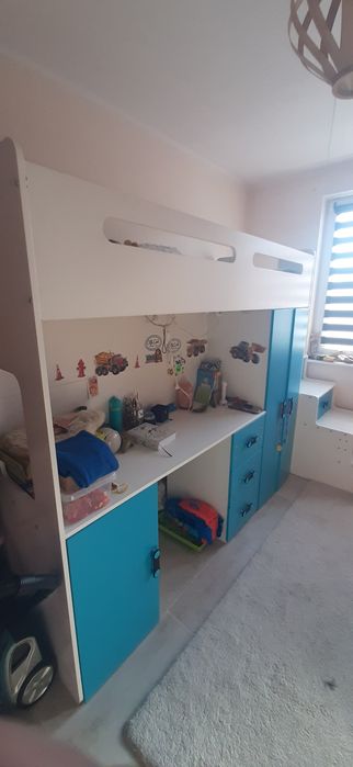 Łóżko piętrowe z biurkiem i schodami.