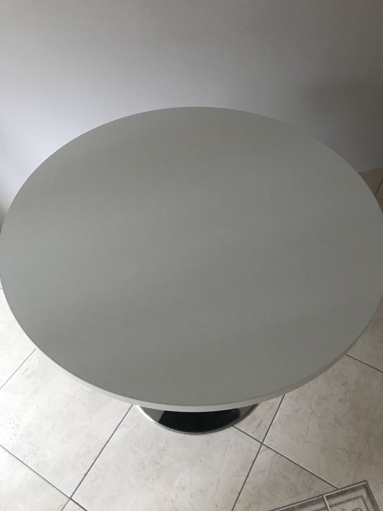 Biały okrągły stół na czarnej nodze i metalowej podstawce, elegancki