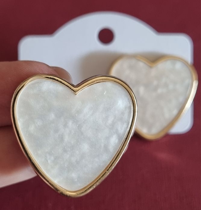 Brincos, de picos, com forma de coração branco delineado a dourado.