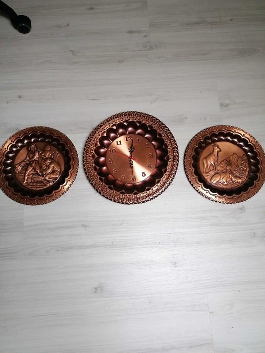 Pratos decorativos em cobre, sendo que um é relógio de parede.