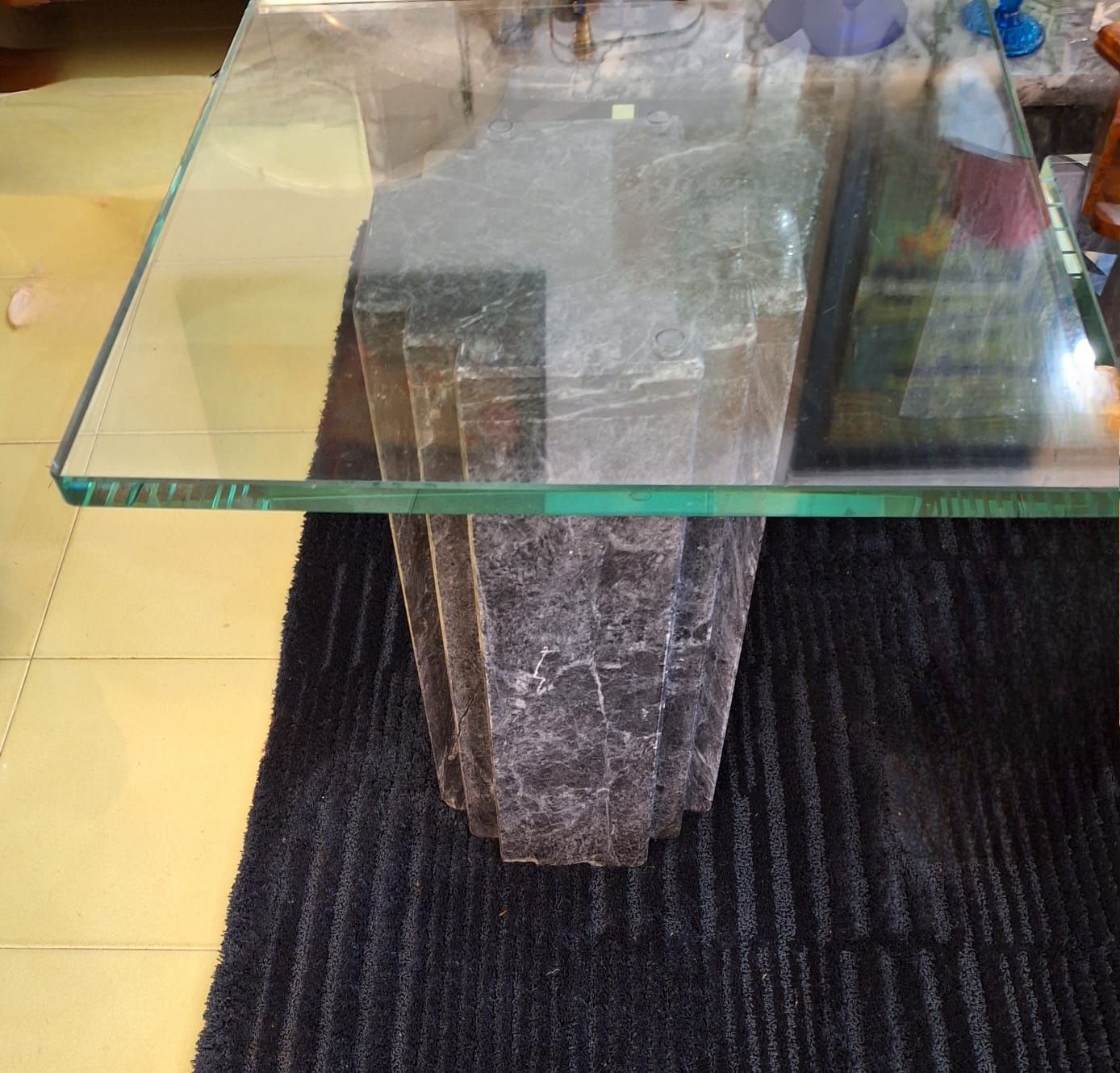 Mesa com apoio de mármore negro maciço e tampo em vidro.