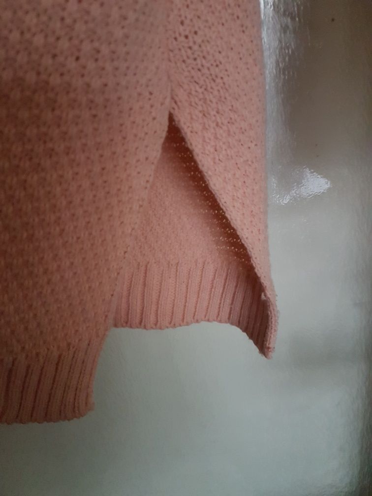 Sweter z okrągłym dekoltem w łososiowym kolorze.