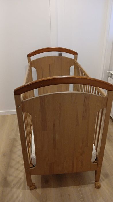 Cama de bebê, em madeira, cor bege.