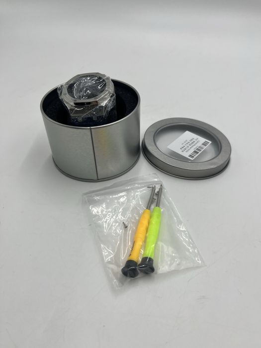 Nowa obudowa do zegarka zapakowana w metalowe pudełko.