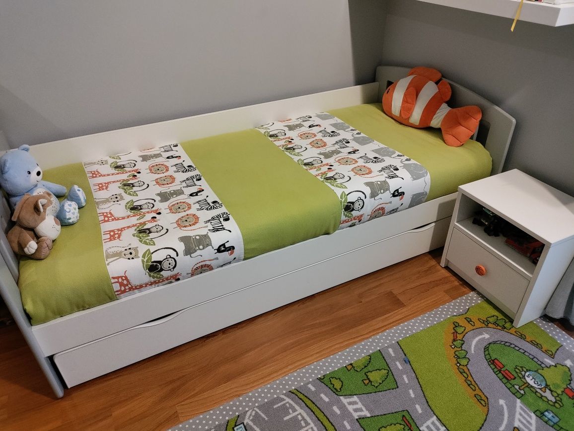 Cama de criança com proteção e mesa de cabeceira