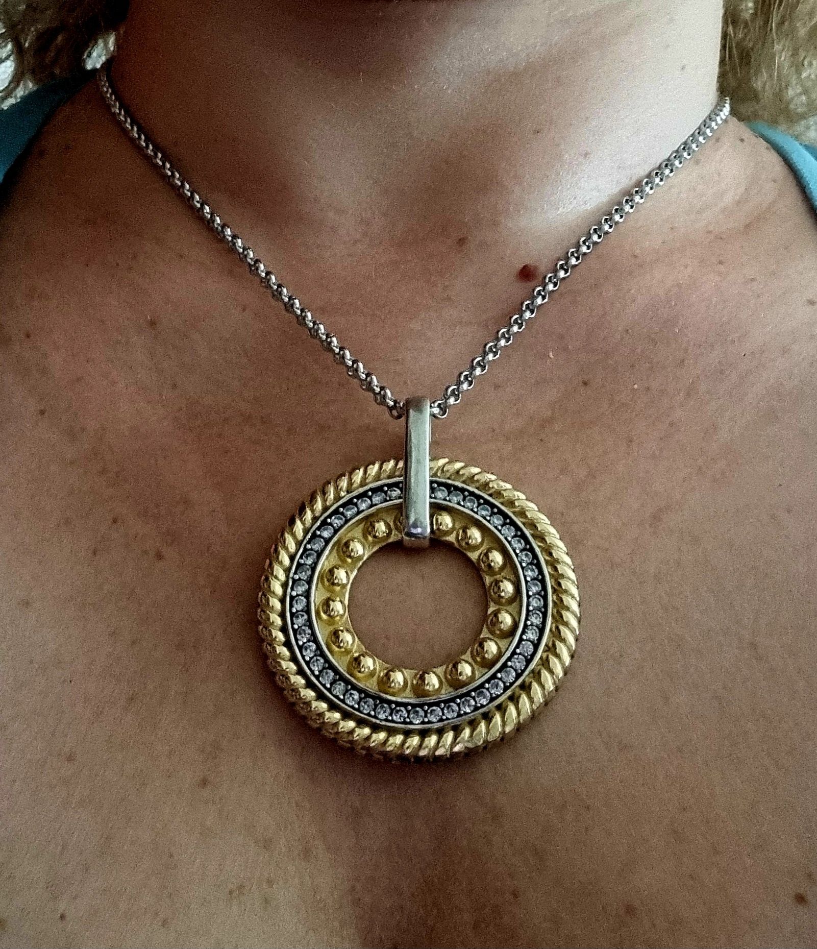 Colar prateado, em aço, com pingente bicolor. Tem extensor