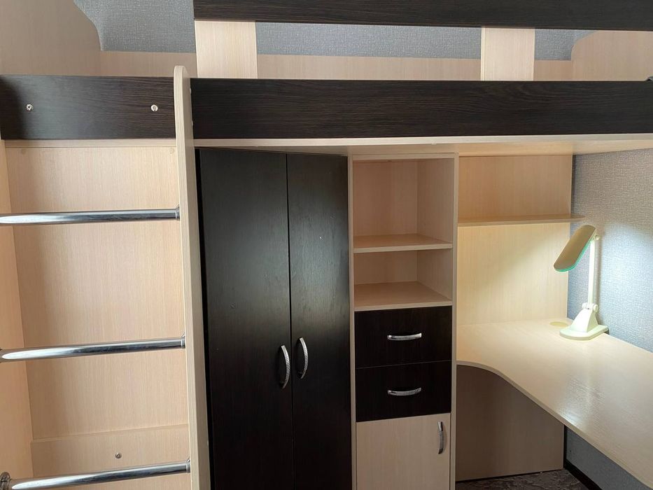 Ліжко двоповерхове разом із столом, поличками та шафою.