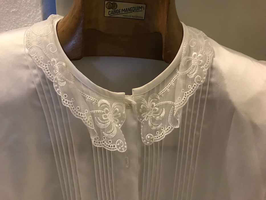 Blusa branca tipo seda com manga comprida.