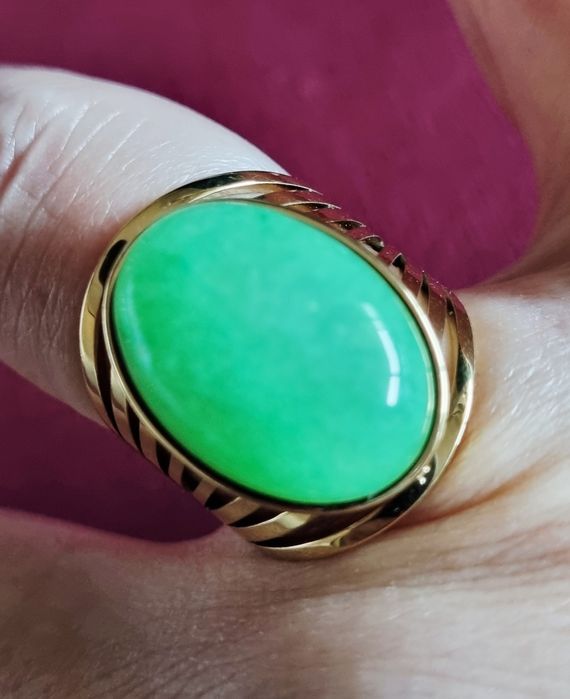 Anel dourado, em aço, com pedra oval verde claro. 18/ajustável