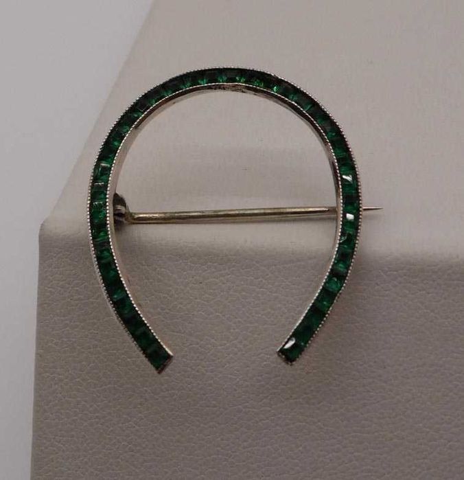 Antyczna srebrna broszka podkowa zielone szmaragdowe kamienie.